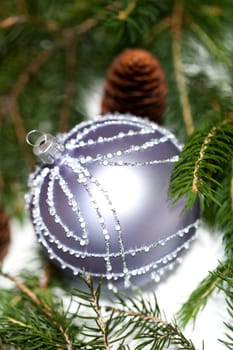 Silver Christmas tree balls in green fir branches with white shiny snow as macro detail