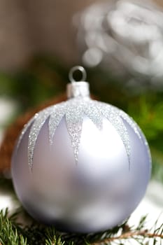 Silver Christmas tree balls in green fir branches with white shiny snow as macro detail