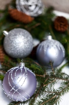 Silver Christmas tree balls in green fir branches with white shiny snow as macro detail