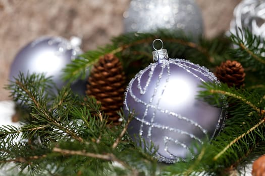 Silver Christmas tree balls in green fir branches with white shiny snow as macro detail