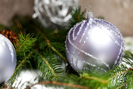 Silver Christmas tree balls in green fir branches with white shiny snow as macro detail