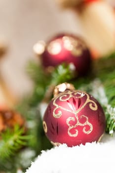 Decoration for Christmas with red and gold Christmas tree balls in front of green fir branches in the background