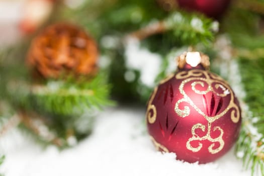 Decoration for Christmas with red and gold Christmas tree balls in front of green fir branches in the background