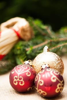 Decoration for Christmas with red and gold Christmas tree balls in front of green fir branches in the background