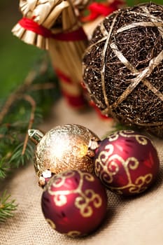 Decoration for Christmas with red and gold Christmas tree balls in front of green fir branches in the background