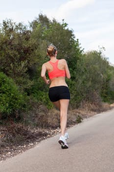 attractive sporty young woman jogging on an outdoor street in daylight