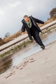 happy active older woman pensioner senior in the open at the sea in autumn