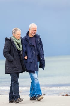 older adult happy couple walks on the beach in autumn lifestyle happiness