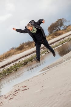 happy active older woman pensioner senior in the open at the sea in autumn