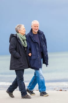 older adult happy couple walks on the beach in autumn lifestyle happiness