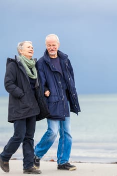older adult happy couple walks on the beach in autumn lifestyle happiness
