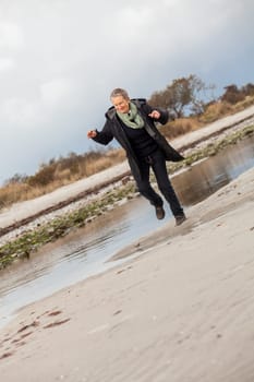 happy active older woman pensioner senior in the open at the sea in autumn