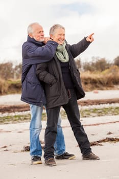 older adult happy couple walks on the beach in autumn lifestyle happiness