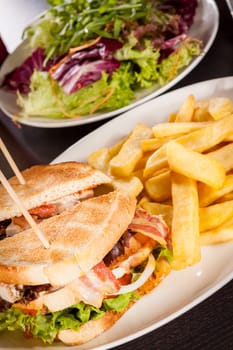 Club sandwich on toasted white bread with bacon and fries fried fries on a plate