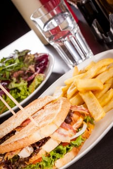 Club sandwich on toasted white bread with bacon and fries fried fries on a plate