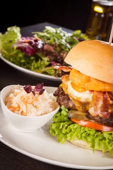 Delicious hamburger cheeseburger with bacon egg and salad on a plate
