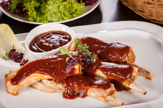 Grilled pork ribs Spareribs with barbecue sauce marinade and herb salad on a plate