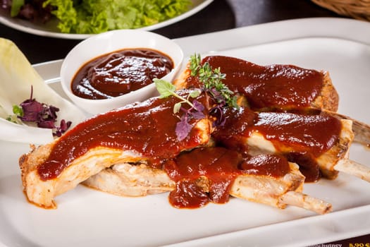 Grilled pork ribs Spareribs with barbecue sauce marinade and herb salad on a plate