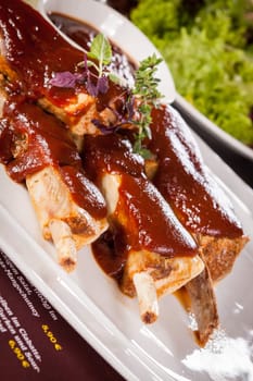 Grilled pork ribs Spareribs with barbecue sauce marinade and herb salad on a plate