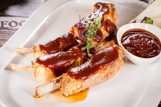 Grilled pork ribs Spareribs with barbecue sauce marinade and herb salad on a plate