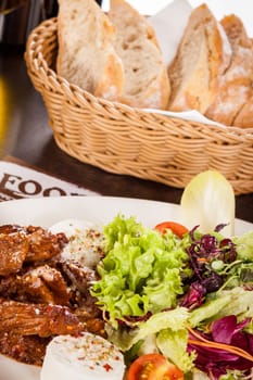Fresh salad with fresh goat cheese and fried beef strips served on a plate