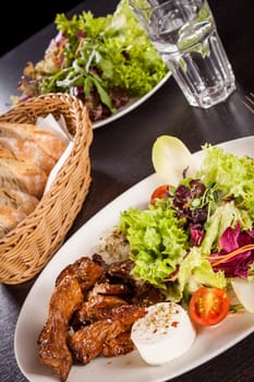 Fresh salad with fresh goat cheese and fried beef strips served on a plate