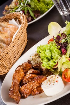 Fresh salad with fresh goat cheese and fried beef strips served on a plate