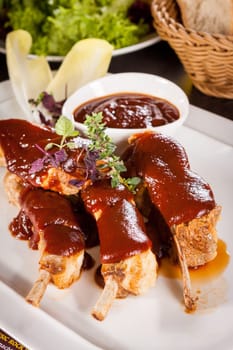 Grilled pork ribs Spareribs with barbecue sauce marinade and herb salad on a plate