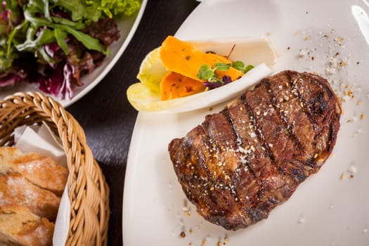 Succulent grilled beef fillet steak with homemade herb butter on a plate isolated against a white background