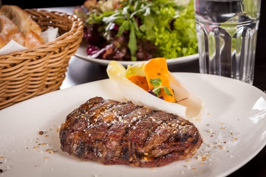 Succulent grilled beef fillet steak with homemade herb butter on a plate isolated against a white background