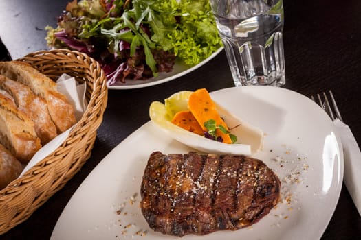 Succulent grilled beef fillet steak with homemade herb butter on a plate isolated against a white background
