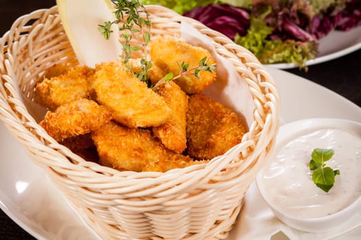 Fresh chicken flails and nuggets golden fried in a basket