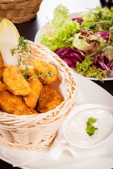 Fresh chicken flails and nuggets golden fried in a basket