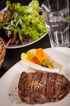 Succulent grilled beef fillet steak with homemade herb butter on a plate isolated against a white background