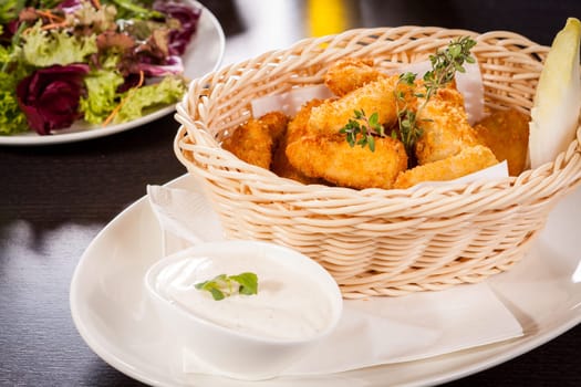 Fresh chicken flails and nuggets golden fried in a basket