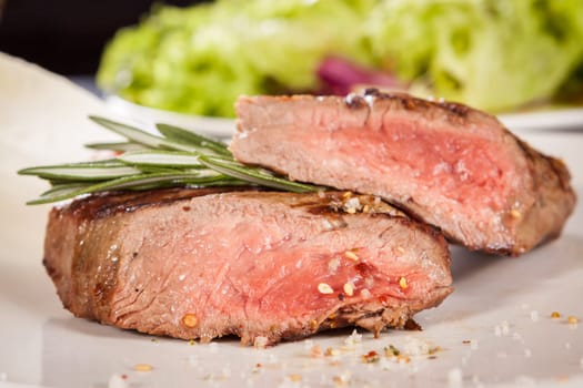 Medium fried beef steak fillet with pepper and rosemary sliced on a plate