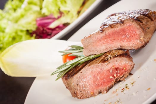 Medium fried beef steak fillet with pepper and rosemary sliced on a plate