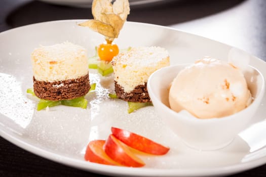 Brownie chocolate brownie with ice cream and plums prepared on a plate