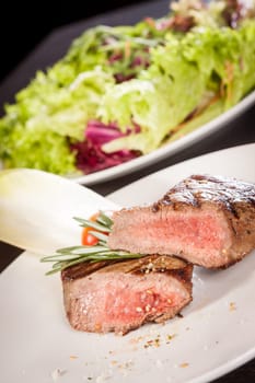 Medium fried beef steak fillet with pepper and rosemary sliced on a plate