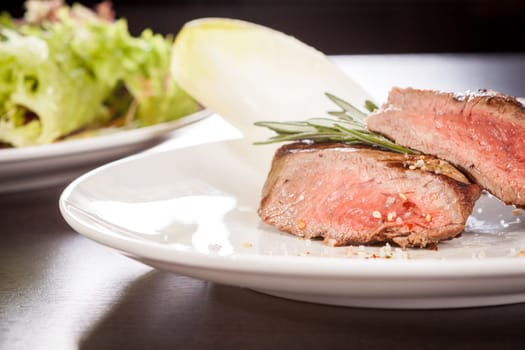 Medium fried beef steak fillet with pepper and rosemary sliced on a plate