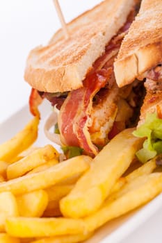 Club sandwich on toasted white bread with bacon and fries fried fries on a plate isolated against a white background