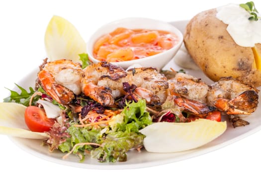 Roasted shrimp on a skewer on mixed salad with dip and foil potato prepared on a plate insulated against a white background