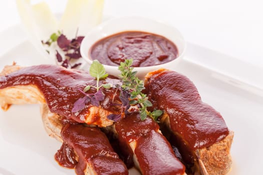 Grilled pork ribs Spareribs with barbecue sauce marinade and herb salad on a plate isolated against a white background
