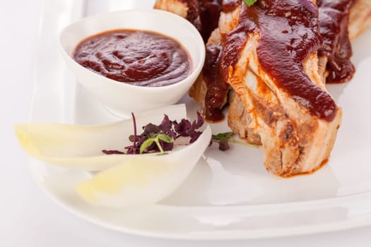 Grilled pork ribs Spareribs with barbecue sauce marinade and herb salad on a plate isolated against a white background
