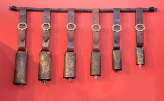 Traditional bells of different sizes made ​​of copper for bullfighting bulls, Spain. Isolated over red background