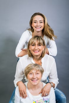 three generations grandmother mother and daughter in portrait against grey background family