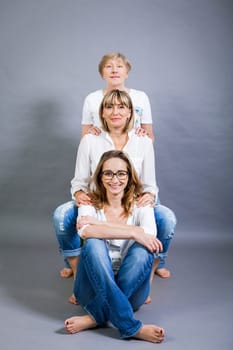 three generations grandmother mother and daughter in portrait against grey background family