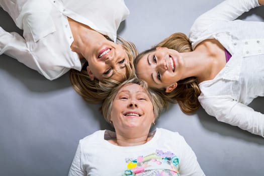 three generations grandmother mother and daughter in portrait against grey background family