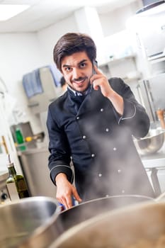 young chef on the phone while cooking in the restaurant kitchen work success stress communication