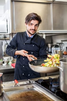 young adult chef in the restaurant kitchen while cooking at the herd preparation